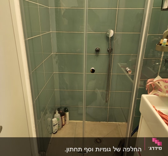מקלחון עם בקבוקי שמפו וסבון על הרצפה